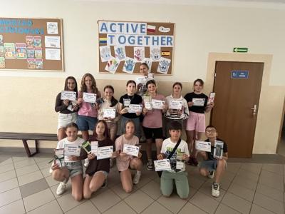 13 uczestników projektu Aktywne przerwy stoi na korytarzu szkolnym z dyplomami.