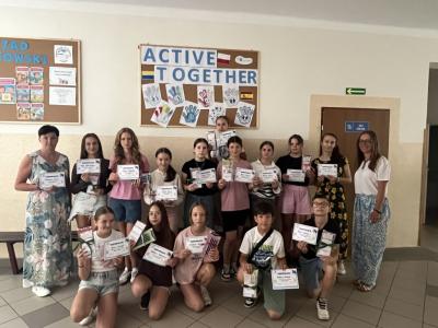 13 uczniów biorących udział w projekcie Aktywne przerwy stoi na korytarzu szkolnym z 3 nauczycielkami trzymając dyplomy