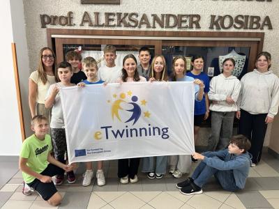 klasa 6b trzyma flagę z logo eTwinning na szkolnym korytarzu