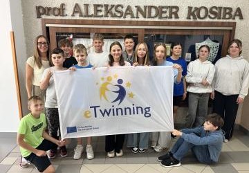klasa 6b trzyma flagę z logo eTwinning na szkolnym korytarzu