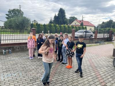uczennica z 4a skacze w klasy i uczy się czasownika to be, reszta dzieci patrzy