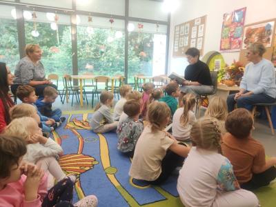 Pani Jola czyta opowiadanie. Przed nią siedzą dzieci na dywanie.