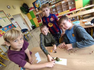 Uczniowie tworzą ślimaka z plasteliny i liści