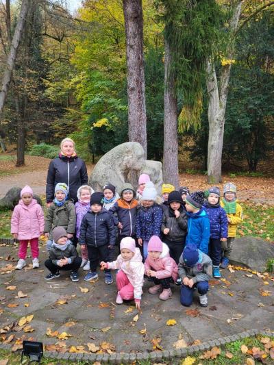 Dzieci ustawione przed kamiennymi misiami w parku pozują do zdjęcia