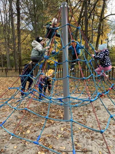 Dzieci wspinają się na rozłożoną sieć z liny na placu zabaw w parku.