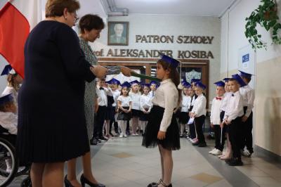 Dyrektor szkoły pani Agnieszka Kapusta pasuje ołówkiem ucznia