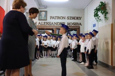 Dyrektor szkoły pani Agnieszka Kapusta pasuje ołówkiem ucznia