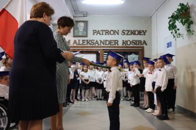 Dyrektor szkoły pani Agnieszka Kapusta pasuje ołówkiem ucznia