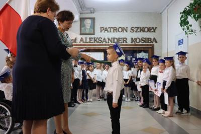 Dyrektor szkoły pani Agnieszka Kapusta pasuje ołówkiem ucznia