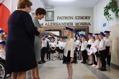 Dyrektor szkoły pani Agnieszka Kapusta pasuje ołówkiem ucznia