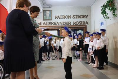 Dyrektor szkoły pani Agnieszka Kapusta pasuje ołówkiem ucznia