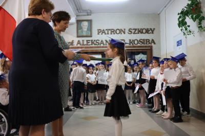 Dyrektor szkoły pani Agnieszka Kapusta pasuje ołówkiem ucznia