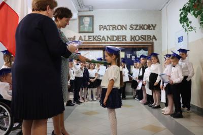 Dyrektor szkoły pani Agnieszka Kapusta pasuje ołówkiem ucznia