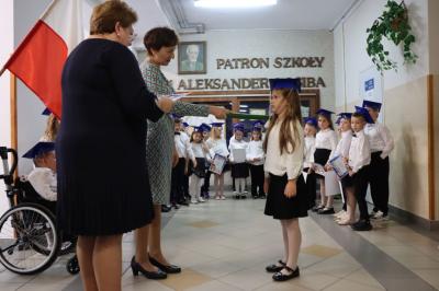 Dyrektor szkoły pani Agnieszka Kapusta pasuje ołówkiem ucznia