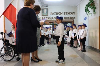 Dyrektor szkoły pani Agnieszka Kapusta pasuje ołówkiem ucznia