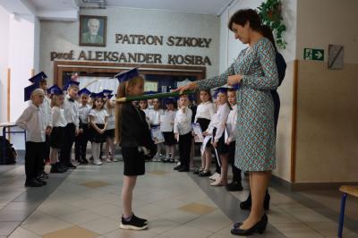 Dyrektor szkoły pani Agnieszka Kapusta pasuje ołówkiem ucznia