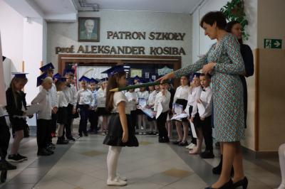 Dyrektor szkoły pani Agnieszka Kapusta pasuje ołówkiem ucznia