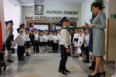 Dyrektor szkoły pani Agnieszka Kapusta pasuje ołówkiem ucznia