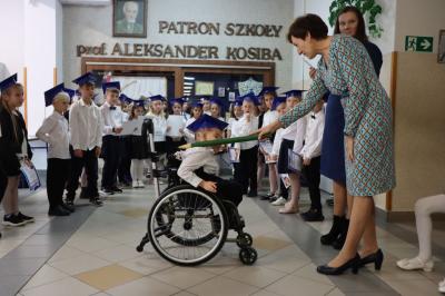 Dyrektor szkoły pani Agnieszka Kapusta pasuje ołówkiem ucznia