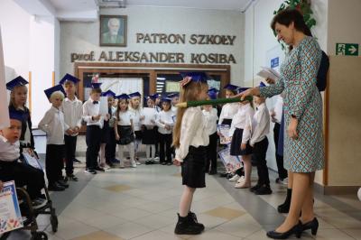 Dyrektor szkoły pani Agnieszka Kapusta pasuje ołówkiem ucznia