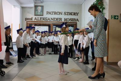 Dyrektor szkoły pani Agnieszka Kapusta pasuje ołówkiem ucznia