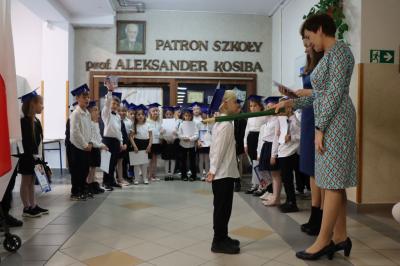 Dyrektor szkoły pani Agnieszka Kapusta pasuje ołówkiem ucznia