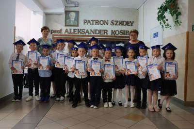 Uczniowie pozują do zdjęcia grupowego wraz z panią dyrektor i wychowawczynią