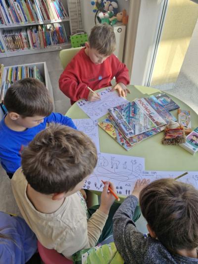 Dzieci siedzą przy stoliku i rozwiązują łamigłówki