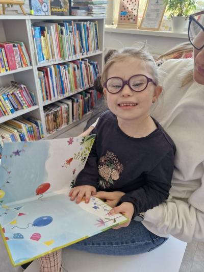 Dziewczynka siedzi i ogląda książkę