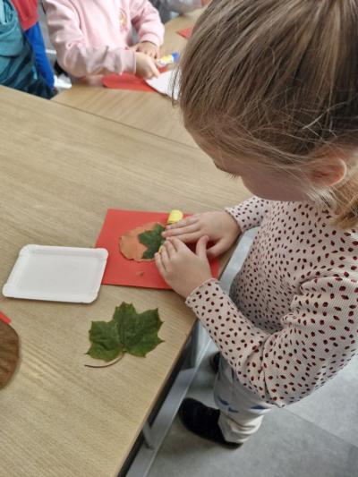 Dziwczynka stoi przy stoliku i wałkuje glinę
