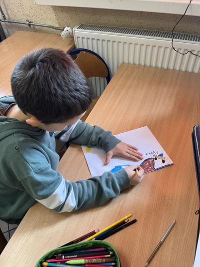 chłopiec rysuje na kartce ilustrację do opowiadania o gołębciy Cher Ami