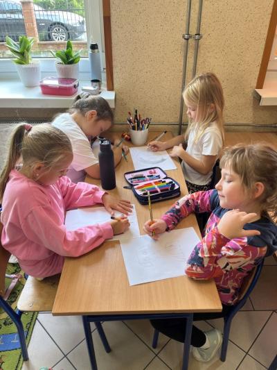 cztery dziewczynki na szkolnej świetlicy rysują zwierzę superbohatera.