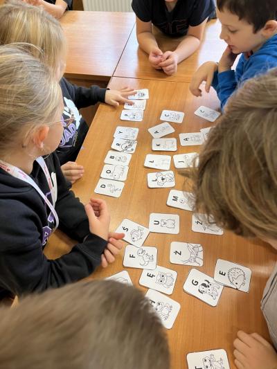 grupa dzieci na szkolnej świetlicy układa zaszyfrowaną wiadomość za pomocą alfabetu zwierzęcego