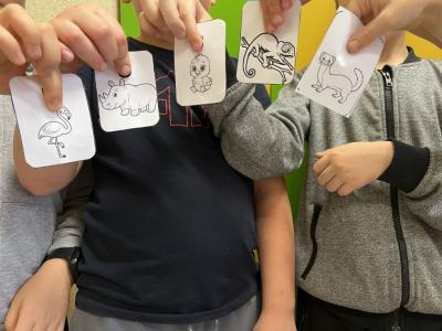 pięciu uczniów trzyma karteczki z ilustracjami zwierząt
