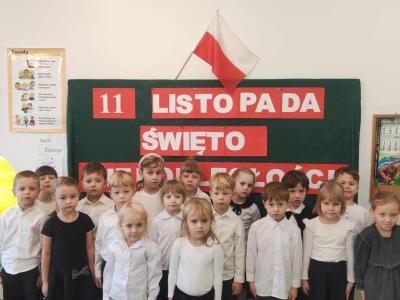 Grupa Sówki ubrana w odświętne stroje z kotylionami na piersi z dumą śpiewa hymn.