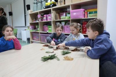 Dzieci siedzą przy stoliku podczas warsztatówrozpoznawania drzew po liściach