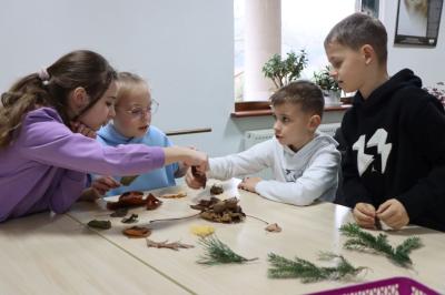 Dzieci siedzą przy stoliku podczas warsztatówrozpoznawania drzew po liściach