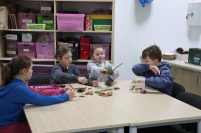 Dzieci siedzą przy stoliku podczas warsztatów rozpoznawania drzew po liściach