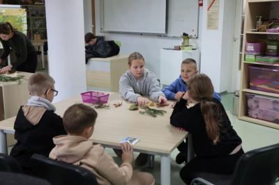 Dzieci siedzą przy stoliku podczas warsztatówrozpoznawania drzew po liściach