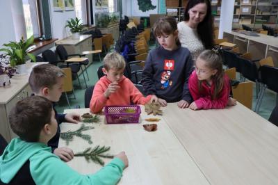 Dzieci siedzą przy stoliku podczas warsztatówrozpoznawania drzew po liściach