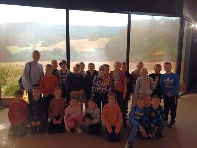 grupa uczniów w sali ekspozycyjnej Cztery pory roku w lesie - w tle wiosenna łąka