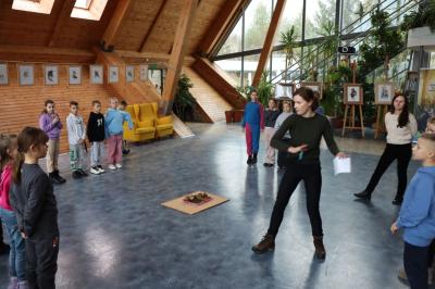 Prowadząca zajęcia warsztatowe na środku sali, wokół stoją dzieci