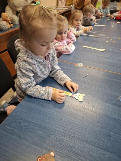 Dziewczynka przykleja kolorowe koraliki do patyczka