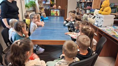 Przedszkolaki siedzą na krzesełkach i oglądają teatrzyk