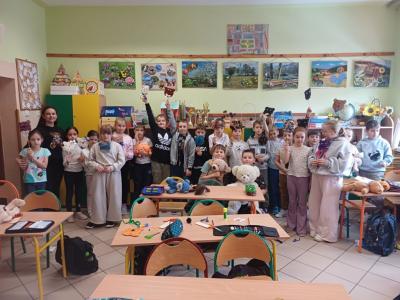 Uczniowie pozuja do zdjęcia, trzymająć przyniesione przez siebie pluszowe misie oraz misie wykonane na lekcji.