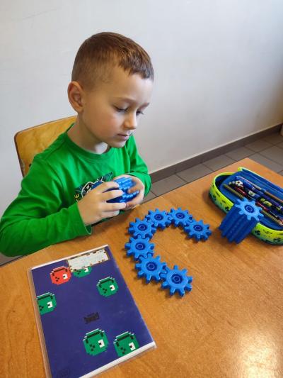 Uczniowie układają wylosowane figury geometryczne i obliczają ile zawierają elementów.