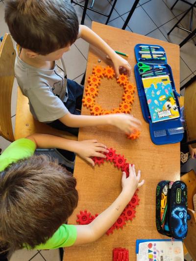 Uczniowie układają wylosowane figury geometryczne i obliczają ile zawierają elementów.