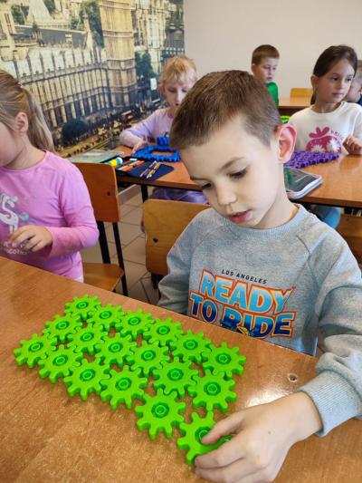 Uczniowie układają wylosowane figury geometryczne i obliczają ile zawierają elementów.