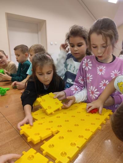 Uczniowie układają platformę z klocków