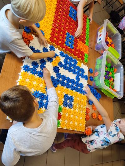 Uczniowie układają domek z różnych figur geometrycznych.